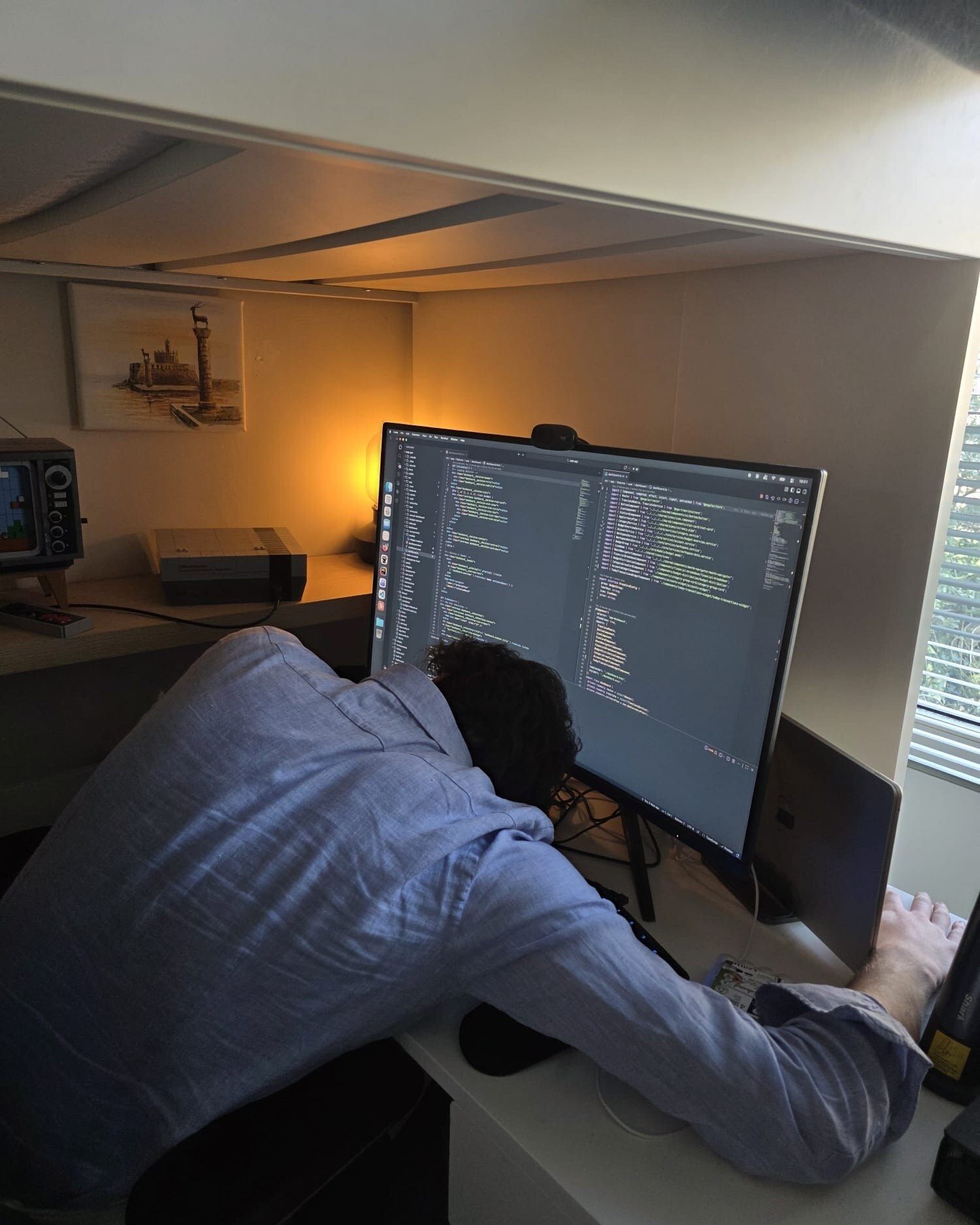 Sven met zijn hoofd op het bureau voor een scherm vol code